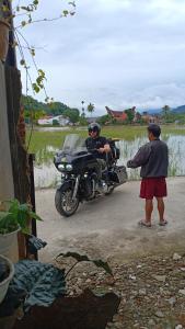 um homem ao lado de um homem ao lado de uma moto em Rosalina Homestay em Rantepao