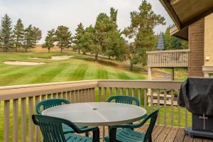 un patio con mesa y sillas y un campo de golf en Sunburst Condo 2739 - Warmly Updated, Leather Furniture and Mountain Views en Elkhorn Village