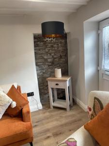 Charming 1-Bed Cottage in Brynmenyn في بريدجيند: غرفة معيشة مع جدار حجري وطاولة