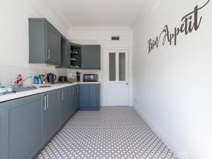 a kitchen with blue cabinets and a tile floor at Longsands Beach, Apartment 4, Tynemouth in Tynemouth