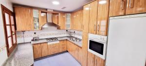 a large kitchen with wooden cabinets and a refrigerator at Vivienda con fines turísticos "Casa Paquita" in Andújar