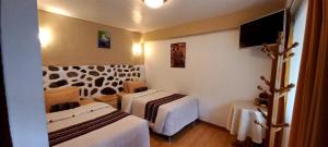 Habitación de hotel con 2 camas y TV en Andean Riverside, en Ollantaytambo