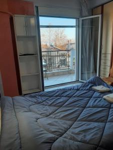 Bett in einem Zimmer mit einem großen Fenster in der Unterkunft Mεζονέτα in Kardítsa