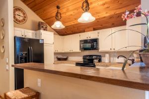 cocina con armarios blancos y nevera negra en Sunburst Condo 2726 - Tri-Level with Spacious Kitchen and Hot Tub Onsite, en Elkhorn Village