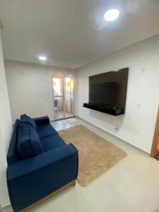 uma sala de estar com um sofá azul e uma televisão de ecrã plano em Apê a 3 min praia de Cotovelo em Parnamirim