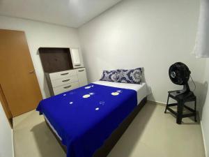 um quarto com uma cama azul e uma ventoinha preta em Apê a 3 min praia de Cotovelo em Parnamirim