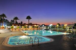 a large swimming pool at night with palm trees at Akti Dimis Hotel in Tigaki