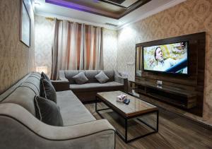 a living room with a couch and a flat screen tv at MAJESTIC HOTEL APARTMENTSماجستيك للشقق الفندقيه in Kuwait