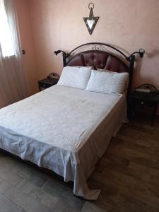 - une chambre avec un grand lit et une tête de lit en bois dans l'établissement Noure Riyad, à Rabat