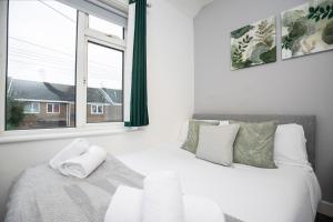 Schlafzimmer mit einem Bett mit weißer Bettwäsche und einem Fenster in der Unterkunft Quiet and Comfy House - Ideal for Contractors in Darlington
