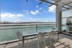una mesa y sillas en un balcón con vistas al agua en AWSA Waterfront Get Away (4018), en Auckland