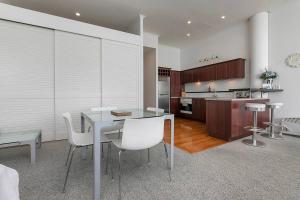 a kitchen with a table and white chairs in a room at AWSA On the Water Luxury (4003) in Auckland