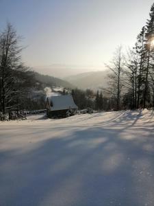 una carretera cubierta de nieve con una casa en la distancia en Domek na Karolce, en Ochotnica Górna
