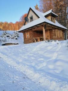 ein Blockhaus im Schnee mit einem Stapel Schnee in der Unterkunft Domek na Karolce in Ochotnica Górna
