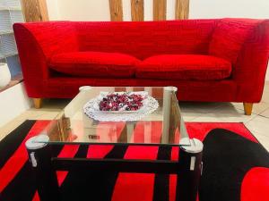a living room with a red couch and a glass table at Coastwave Guest House in Walvis Bay