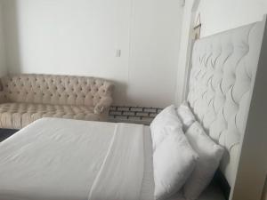 a bedroom with a white bed and a couch at Coastwave Guest House in Walvis Bay