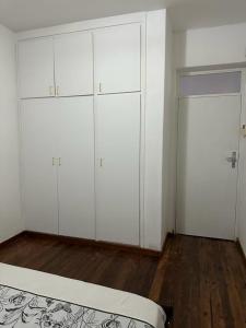 1 dormitorio con armarios blancos y suelo de madera en Coastwave Guest House, en Walvis Bay