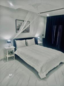 1 dormitorio con 1 cama blanca grande y mesa auxiliar en Magnifique Appartement avec PISCINE, 3 Chambres, 4 Salles de Bain, Salle de Gym et Terrasse, LUXE ET COMFORT aux ALMADIES, en Dakar