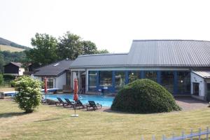 ein Haus mit einem Pool, Stühlen und einem Sonnenschirm in der Unterkunft Haus Ceddy Diemelsee in Diemelsee