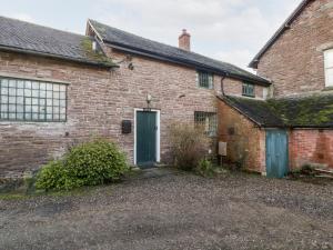 an old brick house with a green door at Yew Tree Cottage in Leominster