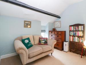 a living room with a couch and a book shelf at Yew Tree Cottage in Leominster