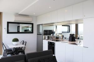a kitchen with white cabinets and a table with chairs at Luxurious Flemington with Stunning Racecourse View in Melbourne