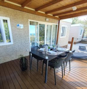 una mesa negra con sillas en una terraza de madera en Mobile House 4 you, Camp Rehut, en Murter