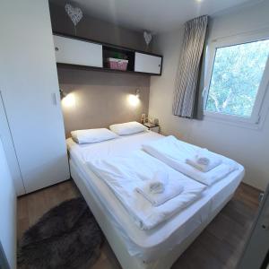 een slaapkamer met een wit bed en handdoeken bij Mobile House 4 you, Camp Rehut in Murter
