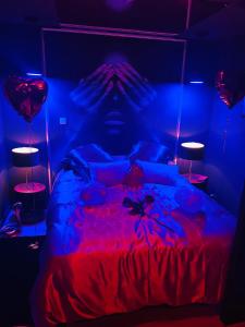 1 dormitorio con 1 cama con luces rojas y azules en Chambre Noire, en Solre-le-Château