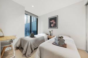 Un dormitorio con dos camas y un escritorio y una ventana. en A Cosmopolitan Hub in CBD Centre, en Melbourne