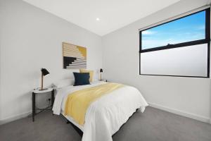 a white bedroom with a bed and a window at Parkside Chic Near Northland in Melbourne
