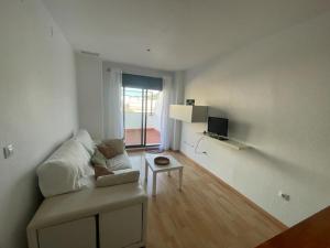 Sala de estar blanca con sofá y mesa en Apartamento turístico Cristóbal Colón, en Huelva