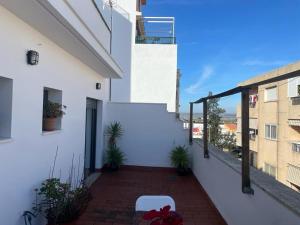 a balcony of a white building with a chair at Apartamento turístico Cristóbal Colón in Huelva