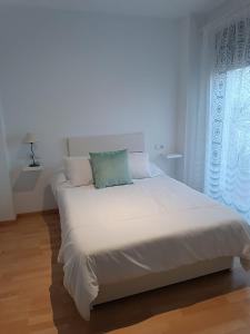 un grande letto bianco in una stanza con finestra di Apartamento turístico Cristóbal Colón a Huelva