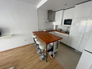 una cocina con encimera de madera y armarios blancos en Apartamento turístico Cristóbal Colón, en Huelva