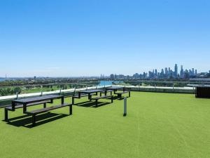 a row of benches sitting on top of a green field at Treetop Tranquillity on Queen in Melbourne
