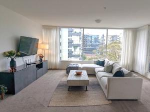 een woonkamer met een witte bank en een tafel bij Treetop Tranquillity on Queen in Melbourne