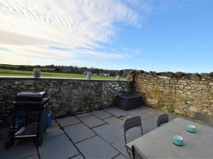 a patio with a table and chairs and a stone wall at 2 Bed in Cartmel 73154 in Cartmel