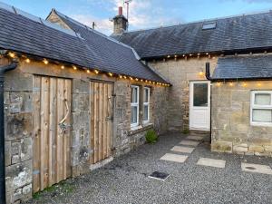 a stone house with a garage with lights on it at Netherraw in Newcastleton