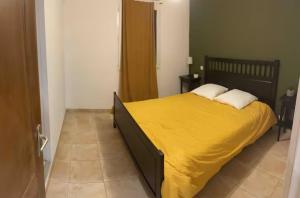 um quarto com uma cama grande e um cobertor amarelo em Maëliette em Montclus