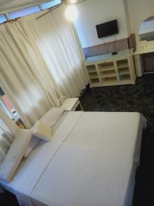 a bedroom with a large white bed with a television at ESTRELLA LOUNGE in Benalmádena