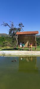 duas crianças sentadas num gazebo ao lado da água em Pousada Mirante dos Ipês - Capitólio - MG em Capitólio