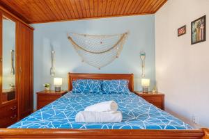 a bedroom with a blue bed with two towels on it at Ocean Blue & Nature Townhouse - Bikes included in Ericeira