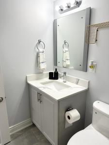 y baño con lavabo, espejo y aseo. en Cozy & Comfortable basement apartment, en Mississauga