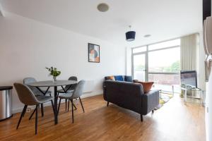 a living room with a couch and a table and chairs at Stylish Northern Quarter 2Bed, Free Parking, WI-FI, Sleeps 4, Central Location, Long term Disc in Manchester