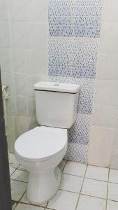 ein weißes WC im Bad mit einer blau-weißen Wand in der Unterkunft Musaria Country Home in Kericho