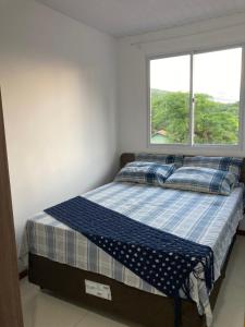 a bed in a room with a window at Recanto das Pedras Floripa in Florianópolis