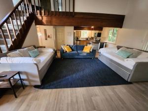 una sala de estar con 2 sofás y una escalera en Lovely Poconos getaway, en Tobyhanna