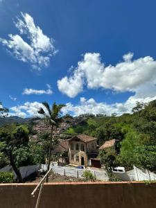 a house on a hill with a palm tree at Pertin da Praça Hostel in Ouro Preto