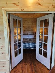 a room with two doors and a bed in a cabin at Horse Farm Retreat in Sherburne